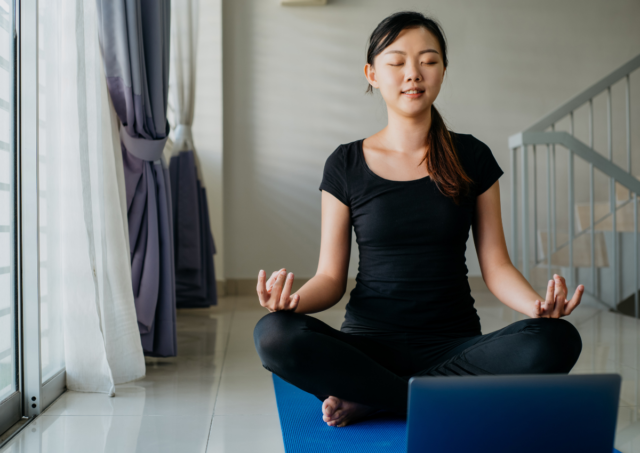 Woman practicing yoga in front of a laptop computer